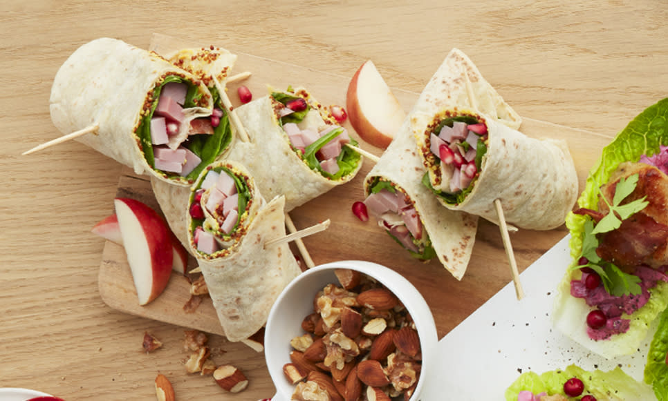 Juleskinke i lompe, rullet sammen og delt i to, servert på trefjøl med eplebåter og en liten skål blandede nøtter.