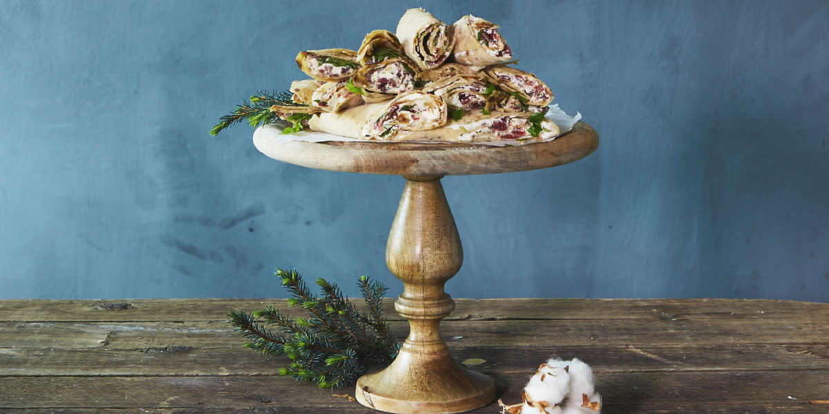 Lefserull med spekematkrem servert på stettfat i tre på rustikk trebord, og pyntet med granbar.