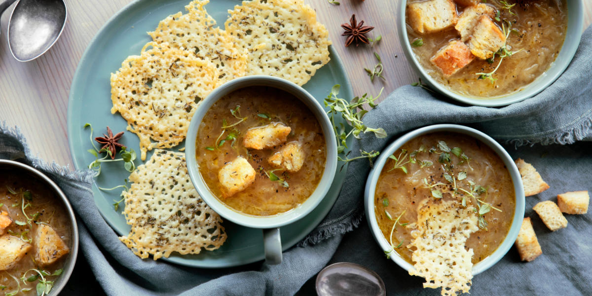 Fransk løksuppe i lyseblå boller med ostechips ved siden av