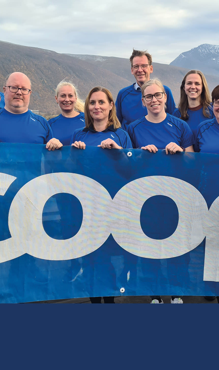 Flere mennesker står med et Coop banner i blått foran fin natur-bakgrunn.