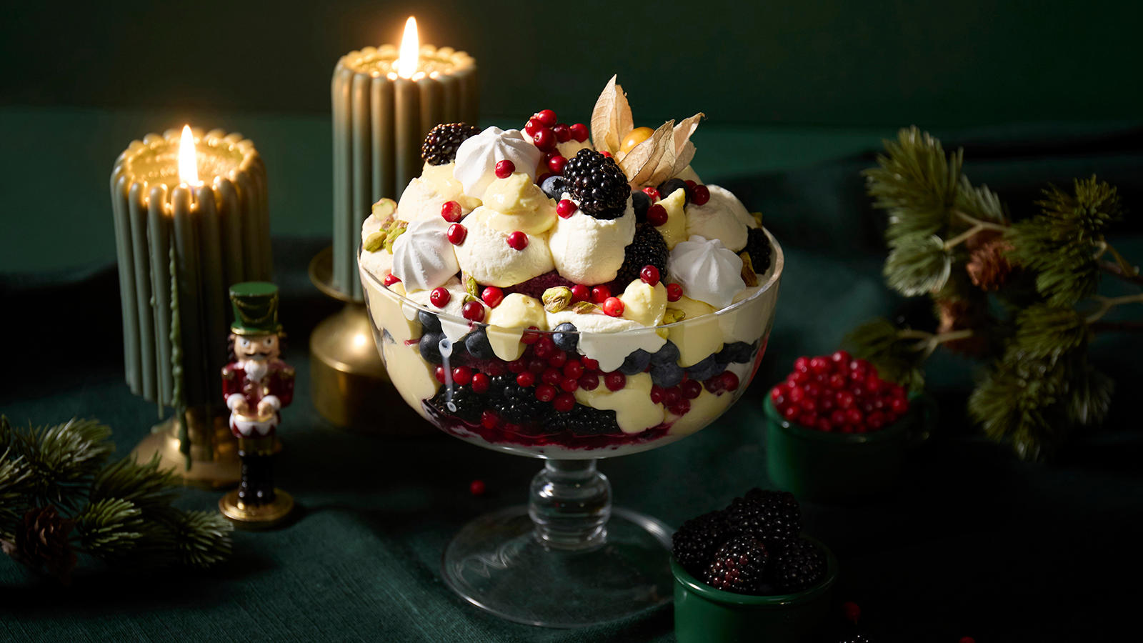 Juletrifle med vaniljekrem og bær pyntet med små marengs og servert i en stor skål med stett.