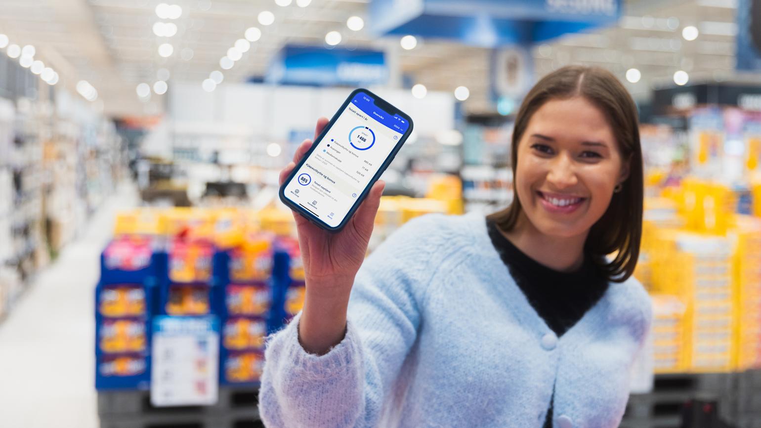 Kvinne viser sitt kjøpeutbytte på mobil i butikk