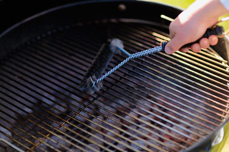 Person som rensker grillen med grillbørste