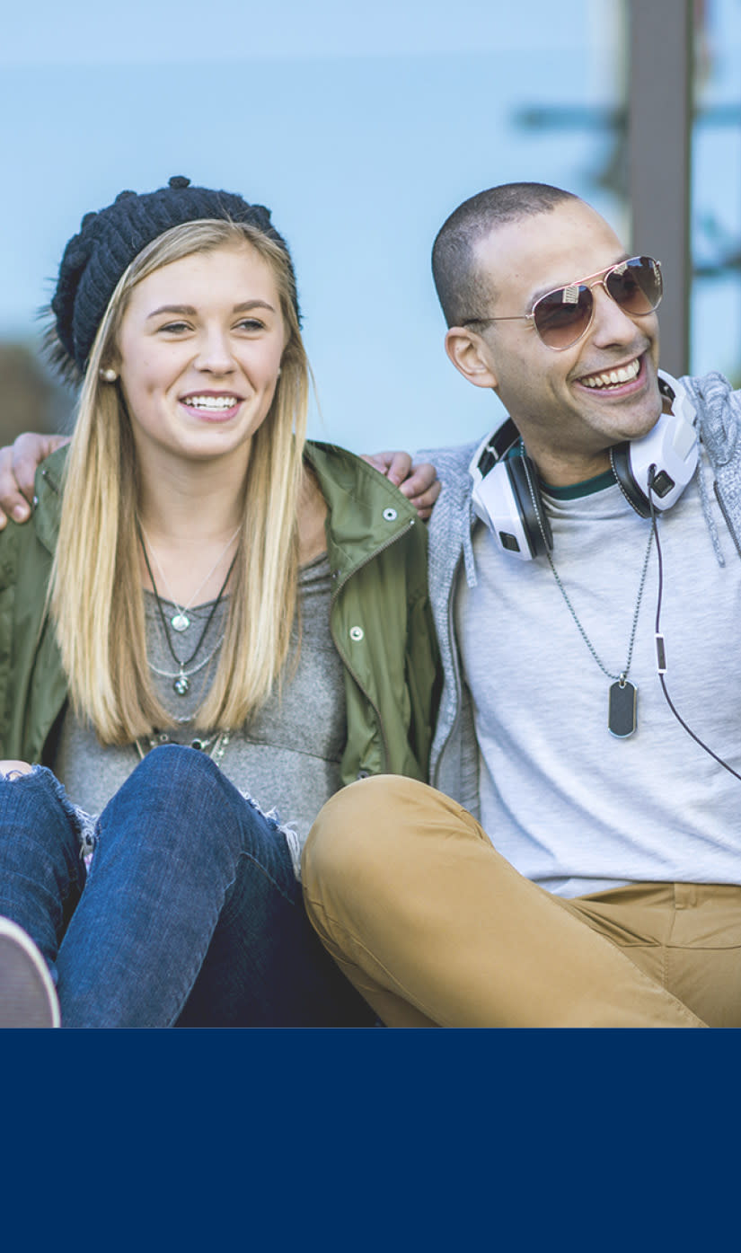 Ungdommer som sitter på en benk og smiler. 