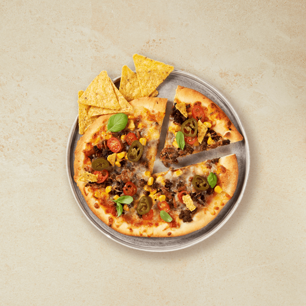 Rund porsjonspizza med tacofyll, toppet med mais, chili, fersk basilikum, jalapeños og tortillachips.