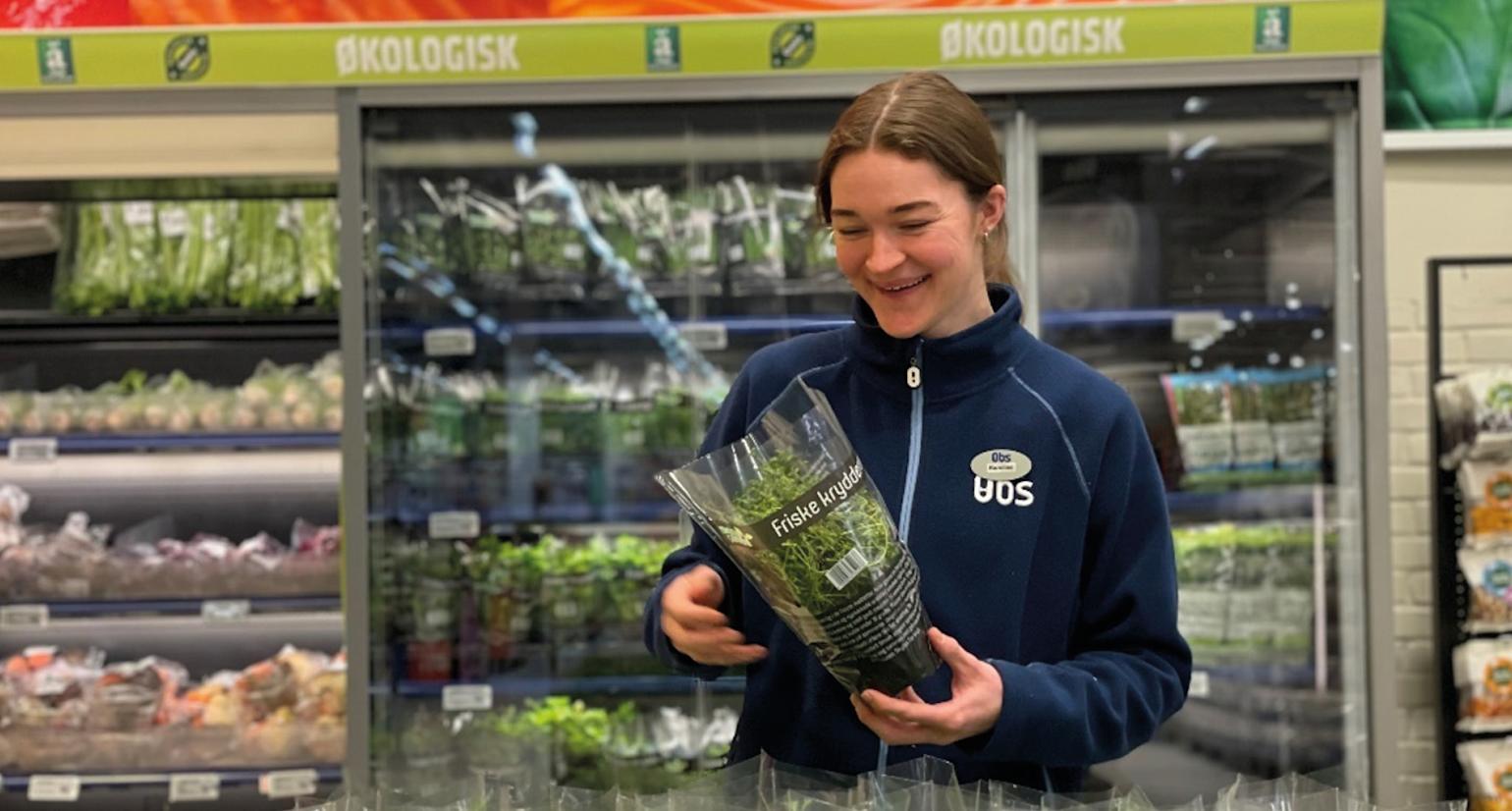 Jente holder en rosmarinplante i hendene og smiler.