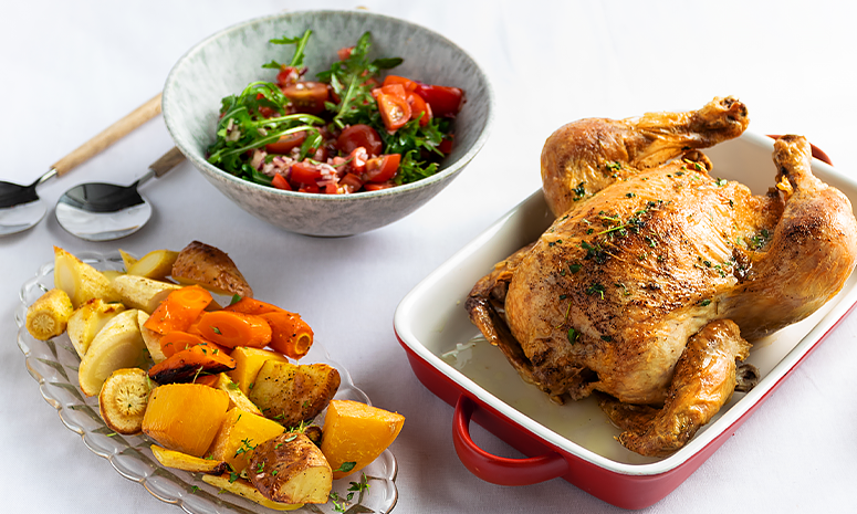 helstekt kylling i ildfast form med ovnsbakte rotgrønnsaker og en tomatsalat på siden