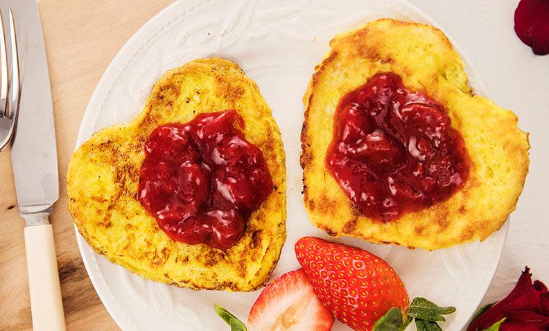 Hjerte - arme riddere, hjerteformede arme riddere med jordbærsyltetøy på toppen, og friske jordbær på siden. Servert på hvit tallerken.