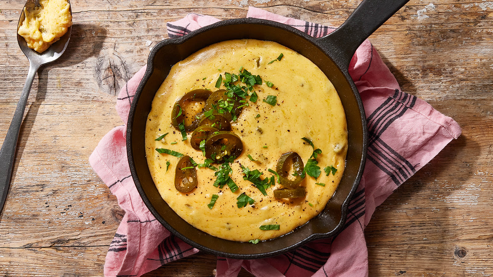 Ostesaus med jalapeño servert i svart støpejernspanne på rustikk trebord.