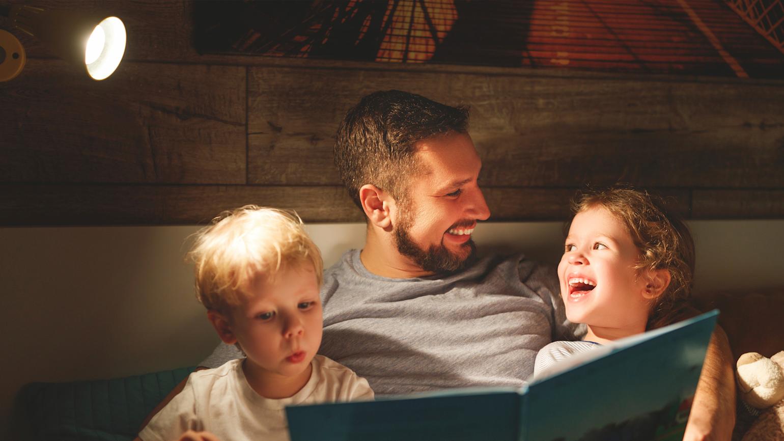 Pappa leser på sengen for barna
