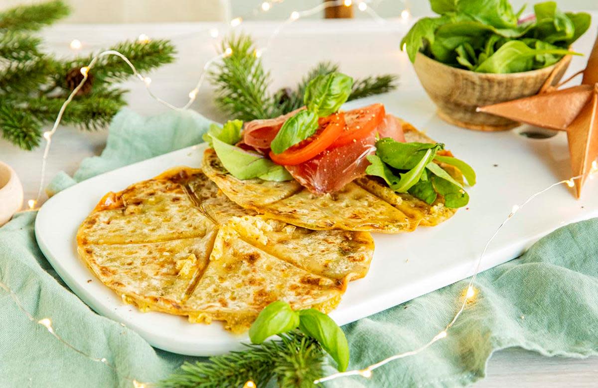 Toast med ost og spekeskinke, laget av lomper. Toppet med tomat, babyleaf salat og fersk spekeskinke, servert på hvitt fat. Hint av jul i bildet.