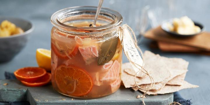 Syltet laks med klementin i glass foran tilbehør som flatbrød og klementinskiver