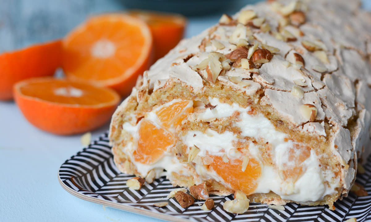 Klassisk Budapestrull med pisket krem og mandarinbåter, servert på mønstret fat, med friske klementiner i bakgrunnen.
