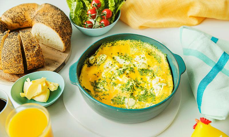 Eggerøre laget i mikrobølgeovnen, i turkis skål, på frokostbord med salat, tomater, juice og lyst horn.