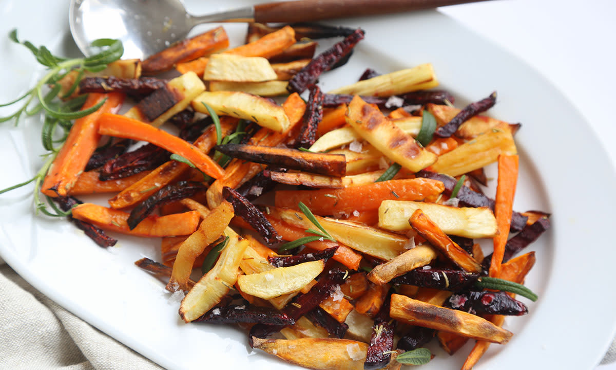 Sprø og saftige ovnsbakte rotgrønnsaker på et hvitt fat. Gulrot, rødbete, pastinakk og kålrabi.