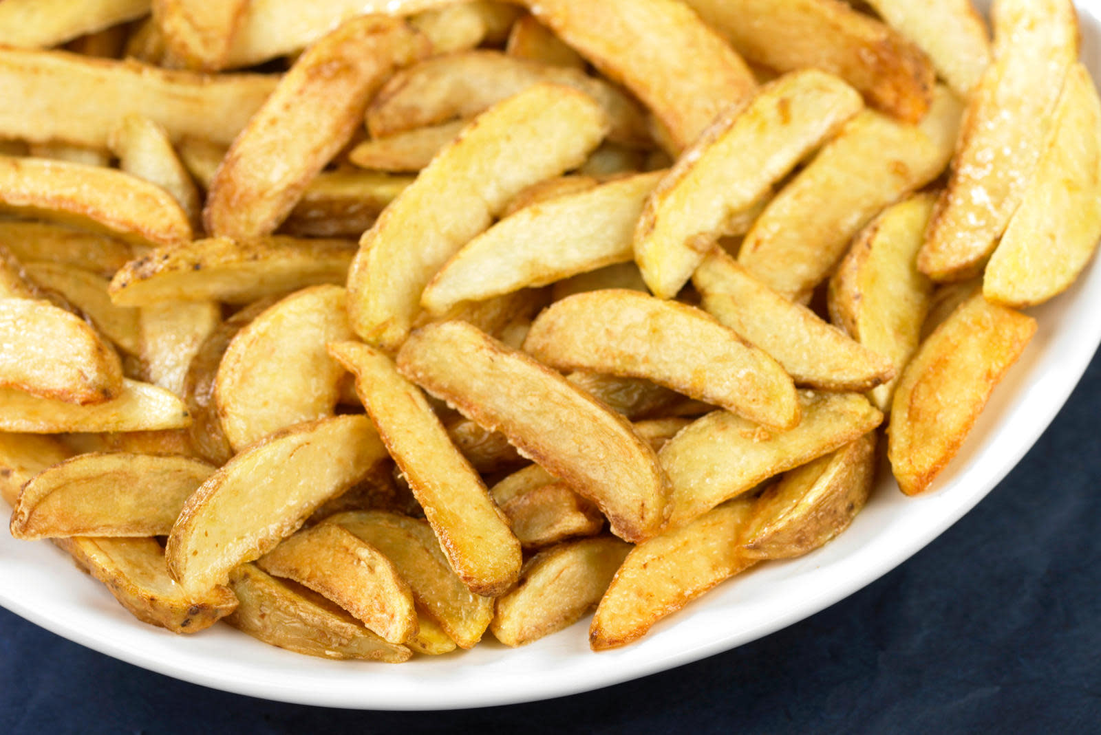 Ovnsstekte potetbåter på hvitt fat. Mørk bakgrunn.