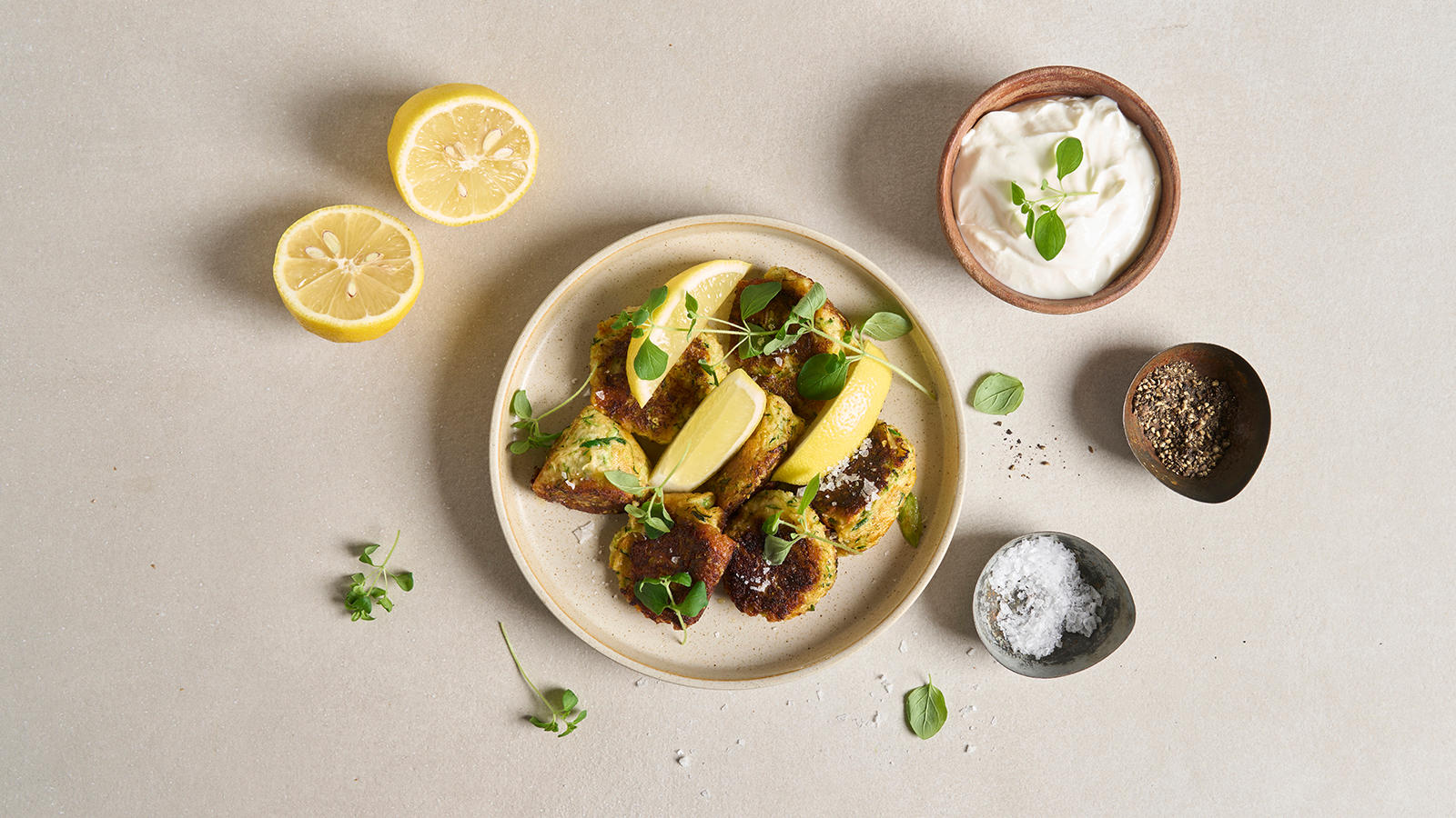Squash- og cheddarsnacks servert på lyst fat med sitronbåter og friske urter. Rundt fatet er det salt, pepper og en frisk yoghurtdressing med aioli.