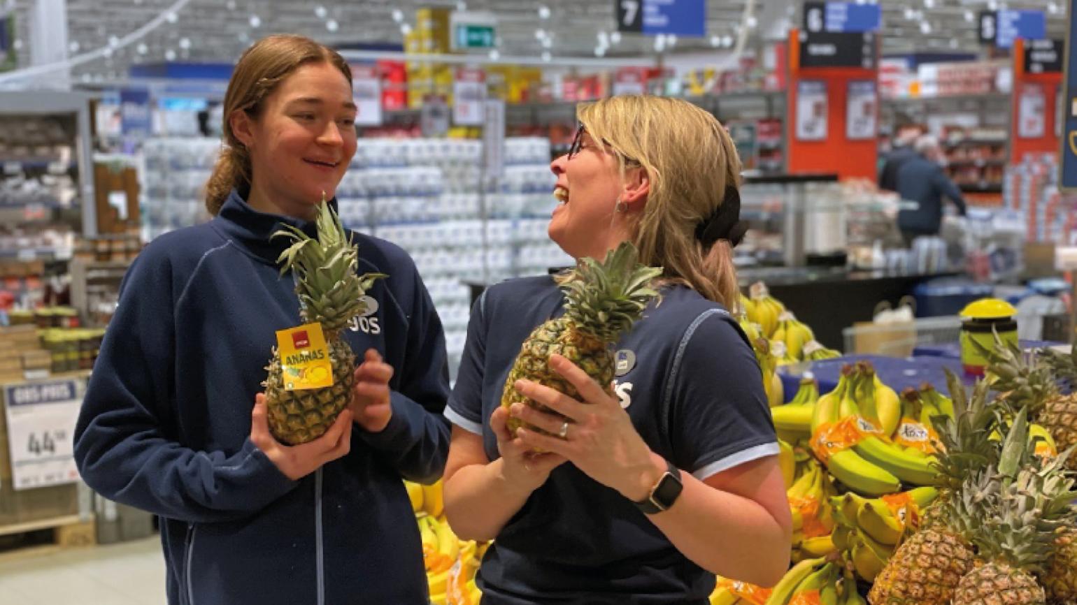 To damer ler med ananaser i hendene.