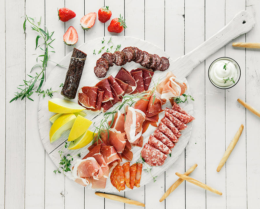 Sommerlig spekefat med forskjellige pølser, skinker, melon, jordbær, dip og grissini.