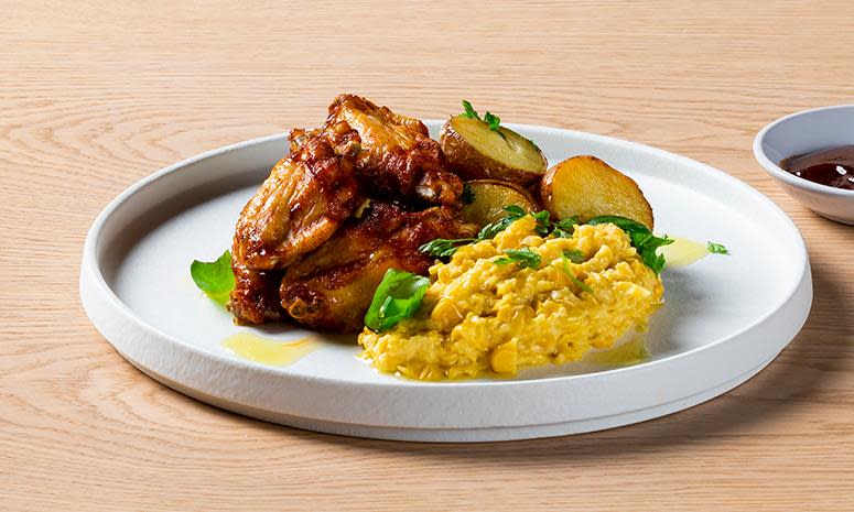 BBQ kylling vinger på en tallerken sammen med maiskrem.