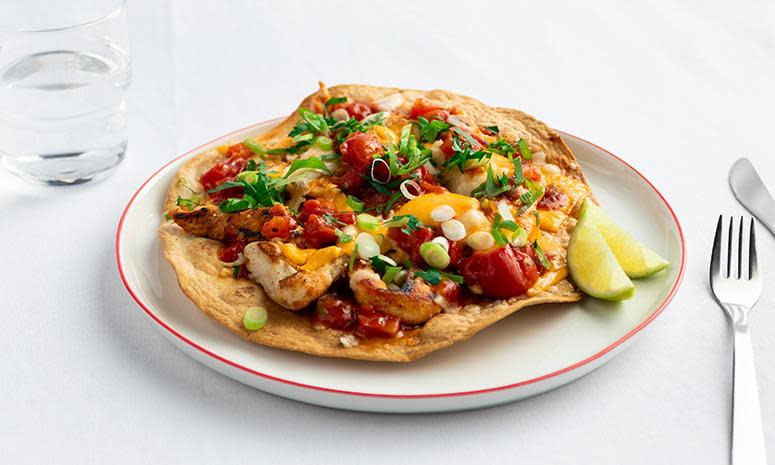 Tortilla med kylling og avokado på hvit tallerken med glass vann