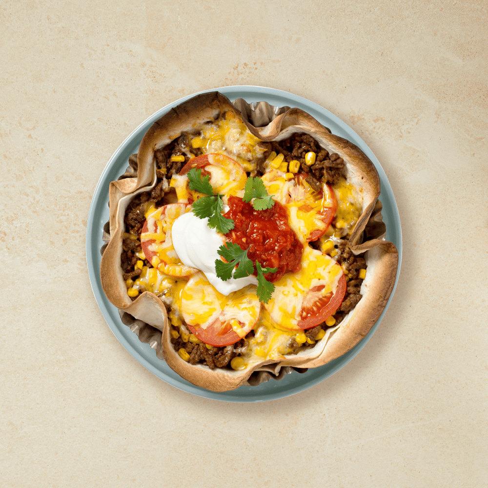 Tacopai med tortillalefser som bunn, fylt med kjøttdeig og mais, og toppet med tomat og ost.