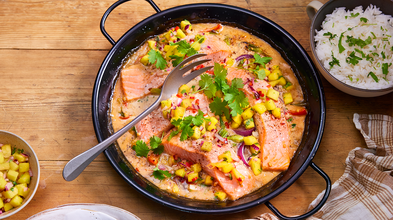 Asiatisk laks i form med mangosalsa, servert med en skål ris på høyre side og en skål mangosalsa på venstre side.