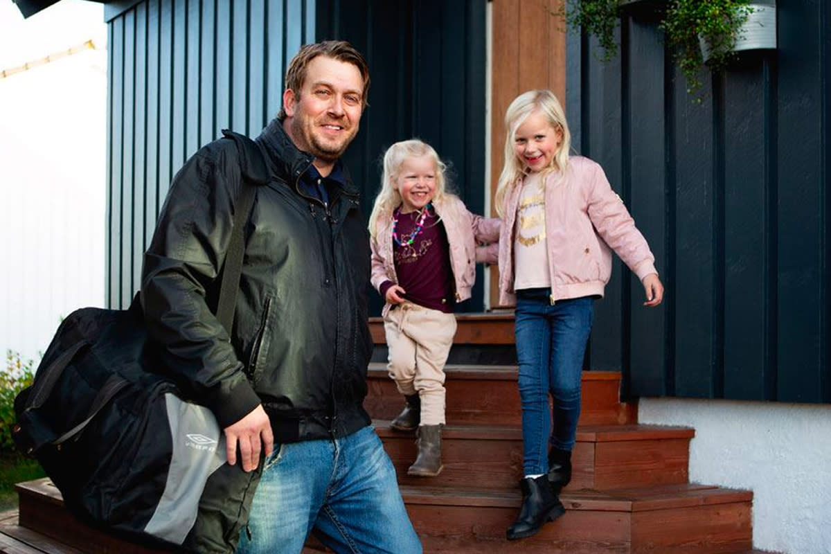 Far med to barn på vei ut av huset sitt