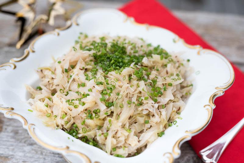 Hjemmelaget surkål på lyst gullkantet fat, med julerød serviett på siden.