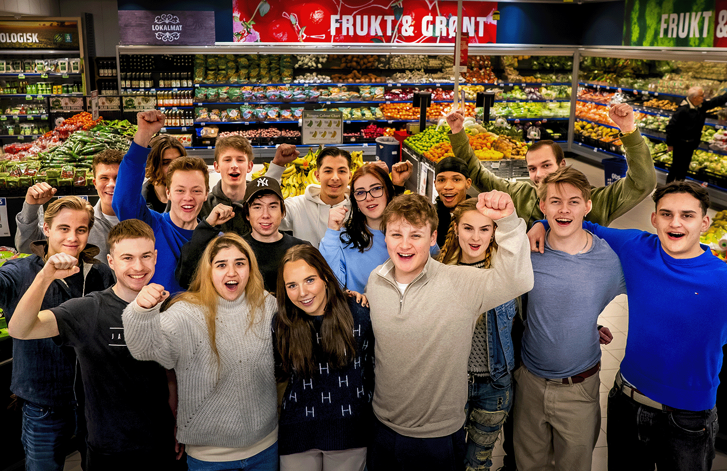 lærlinger står i frukt og grønt avdelingen i en matbutikk og jubler.