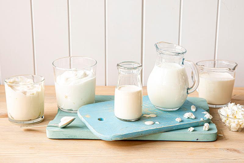 Rester av fløte, rømme og melk i diverse gjennomsiktige glass, mugger og krus på blåmalt trefjøl.