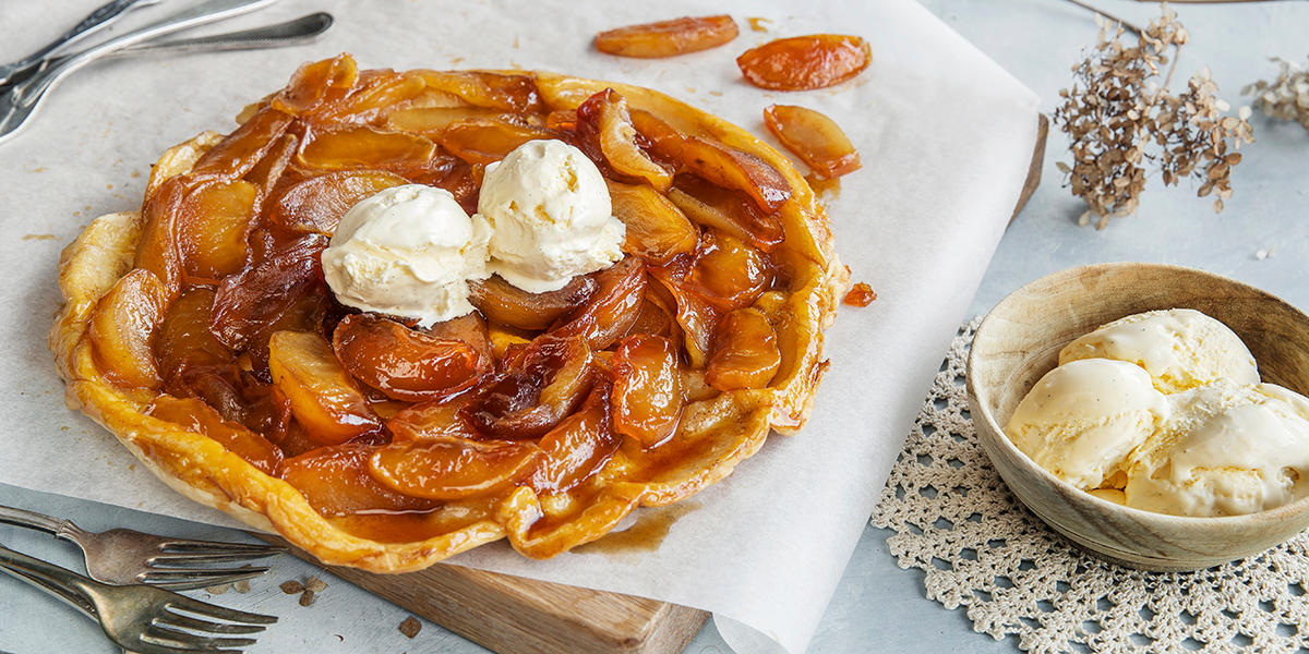 Tarte tatin - fransk epleterte, servert på lys trefjøl med hvitt bakepapir. Iskrem ved siden av.