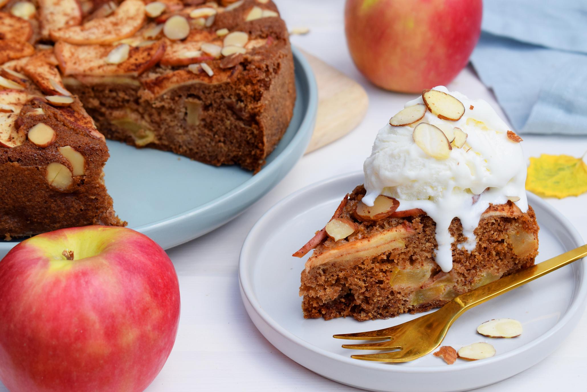 Saftig eplekake med yoghurt i deigen, servert på lyse tallerkner, med smeltende vaniljeis på toppen og et dryss skivede mandler.
