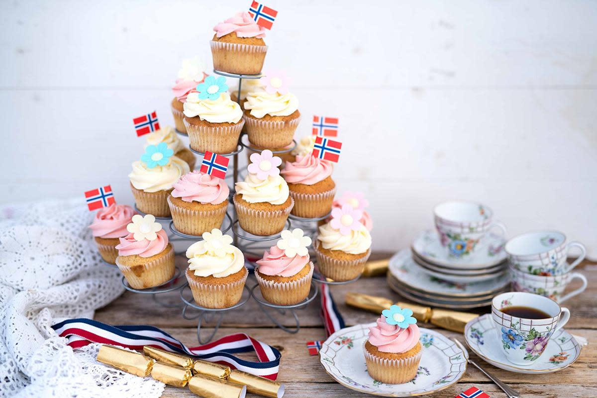 Vaniljemuffins med hvit sjokoladekrem i rosa og hvitt servert i muffinstårn på 17.Mai-dekket bord med kaffeservise.