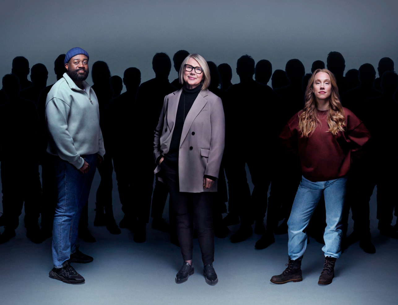 Tre coop-medlemmer står foran en mengde mennesker som ser ut som skyggerd