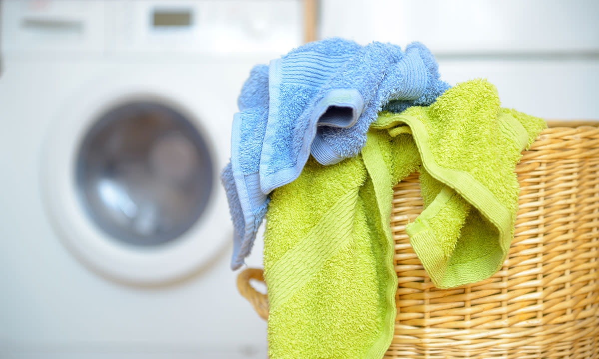 Håndklær i skittentøyskurv med vaskemaskin i bakgrunnen