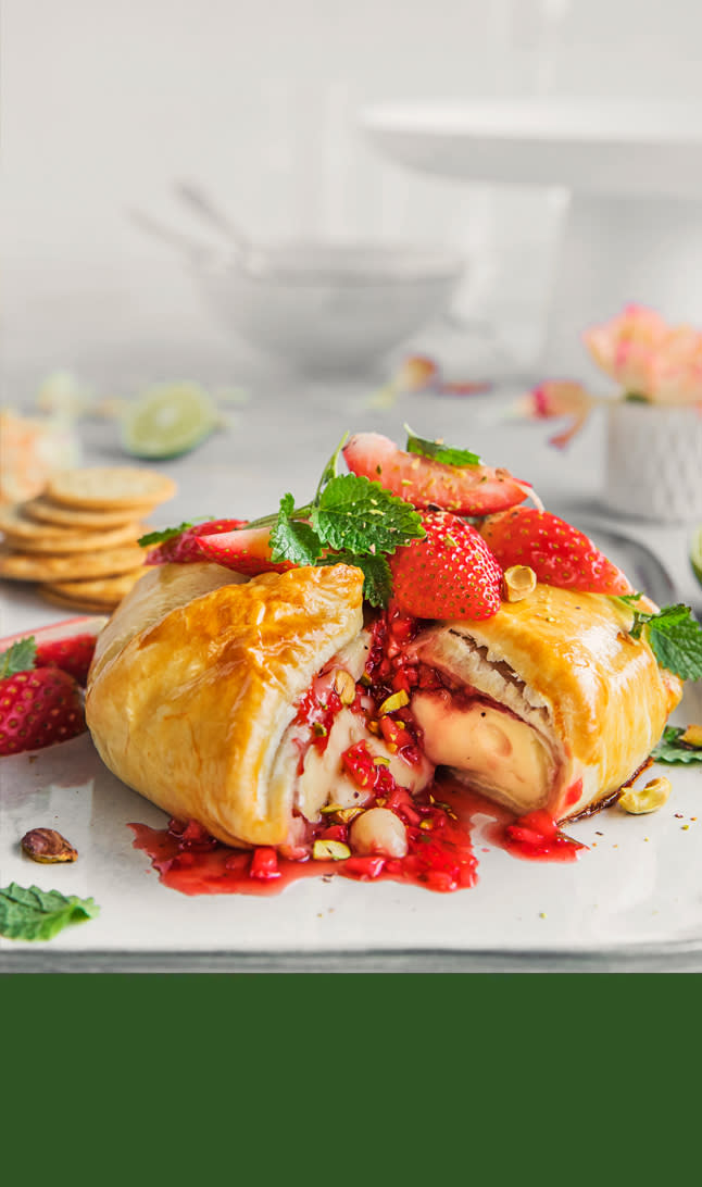 Parmesan stykke med revet parmesan foran på en fjøl øverst og grønn bakgrunn nederst