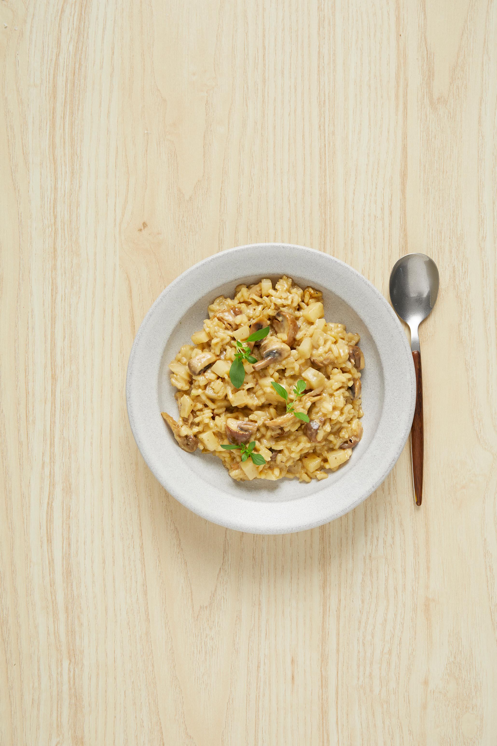 Sopprisotto med jordskokk i en hvit skål med en skje ved siden av