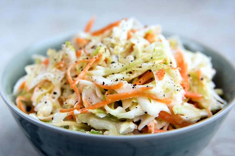 Tilbehøret som rocker pølsefesten, coleslaw med kål og gulrot i en skål.