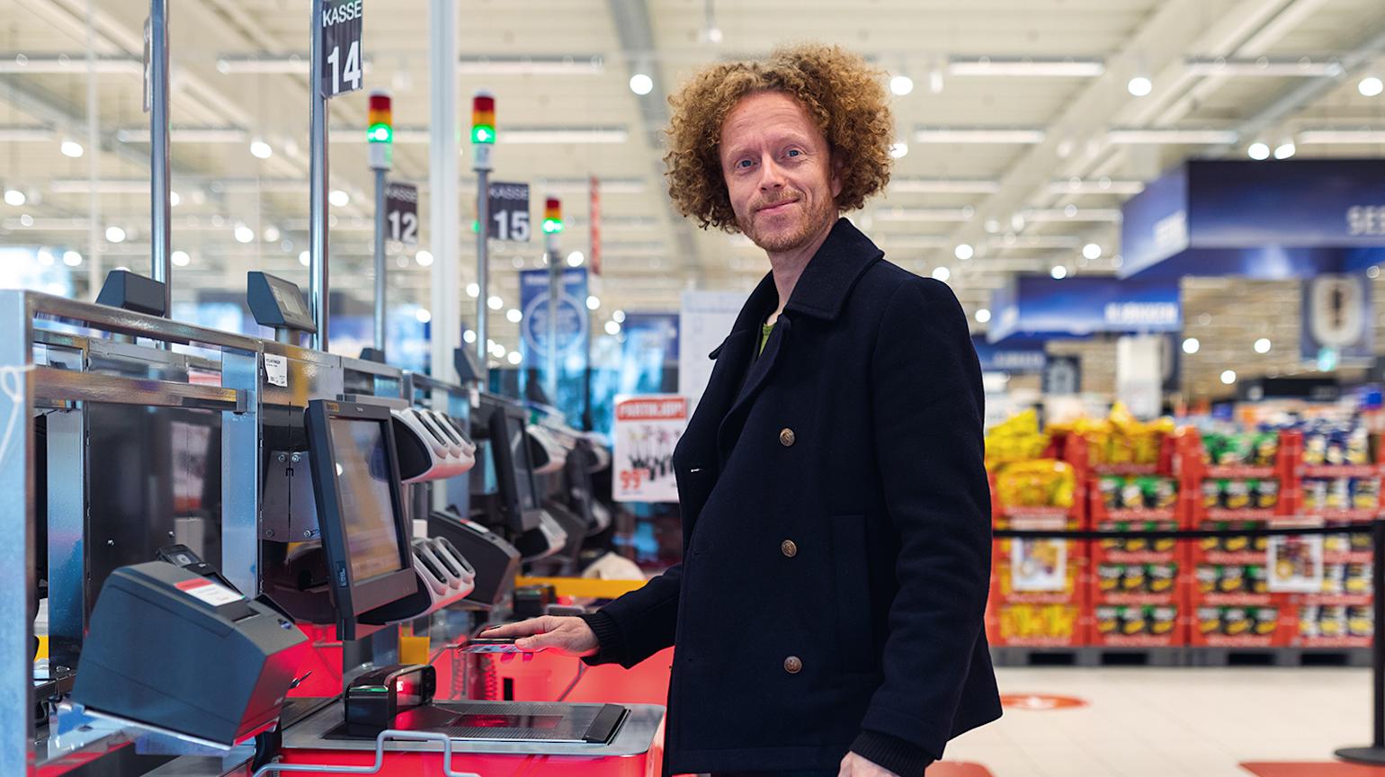 Mann scanner mobilen i selvbetjeningskasse