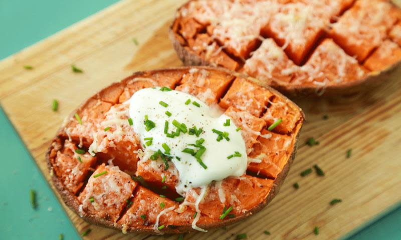 Rask bakt søtpotet delt i to på langs, gratinert med ost, og toppet med rømme og hakket gressløk.