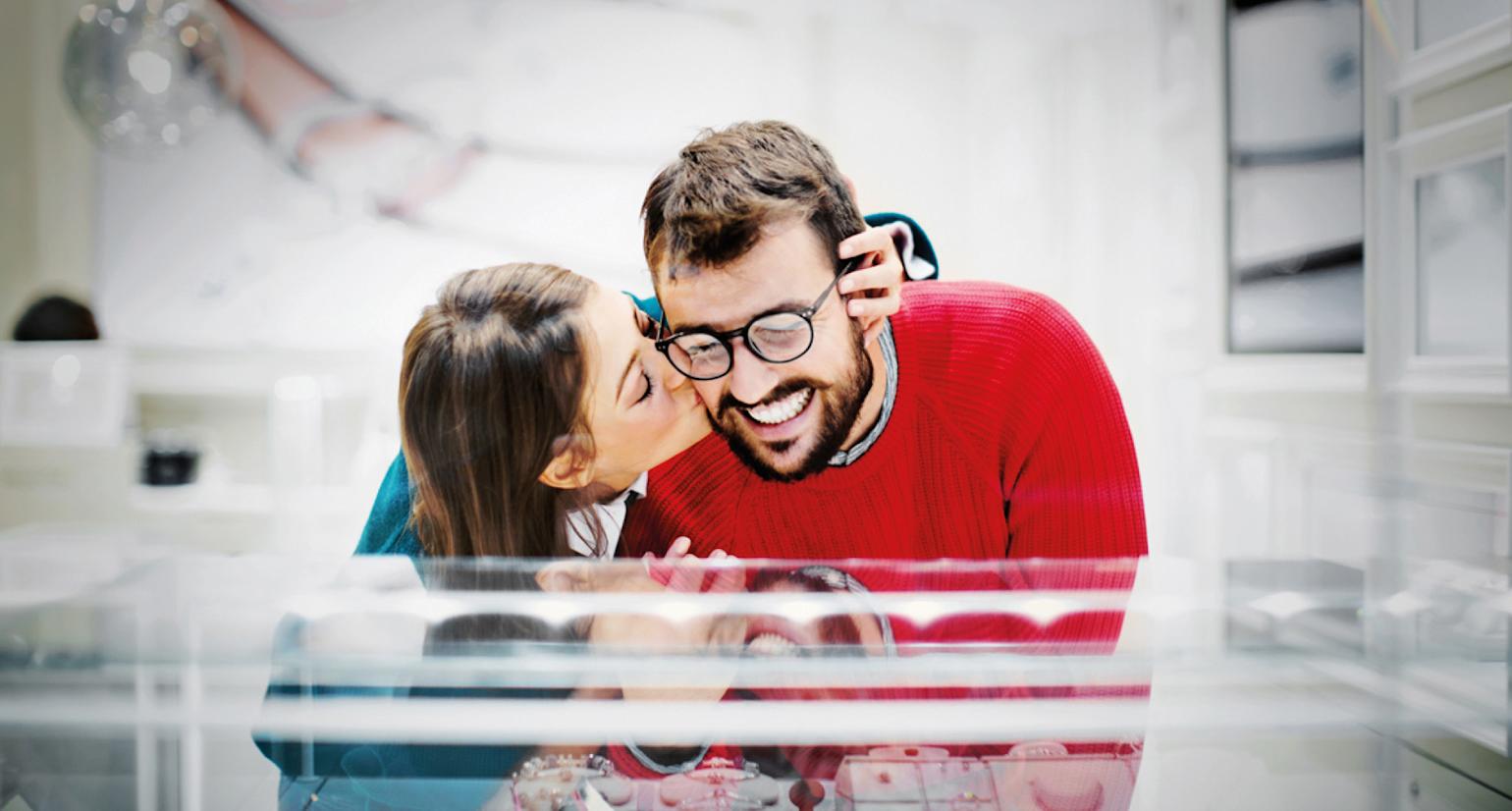 Bilde av en kvinner som kysser en mann på skinnet mens hans smiler.