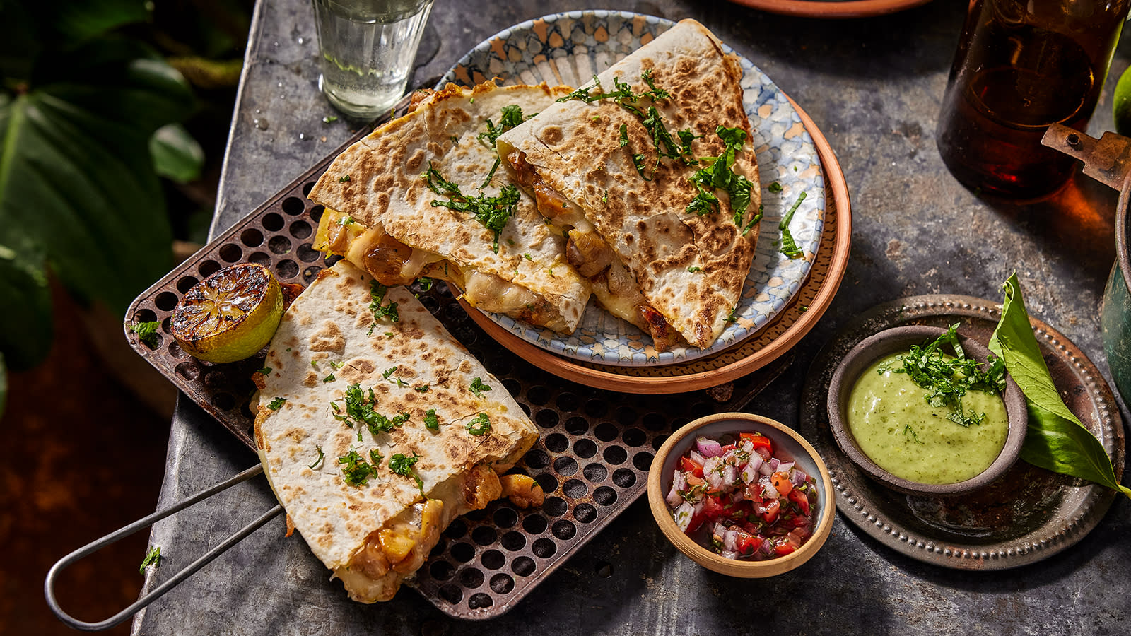 Quesadillas med kylling og ost, delt i stykker og servert med grønn avokadosalsa og grillet lime.