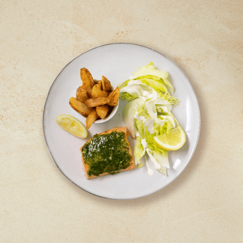 Ovnsbakt laks med pesto, båtpoteter, salat og sitronbåter, servert på en hvit tallerken