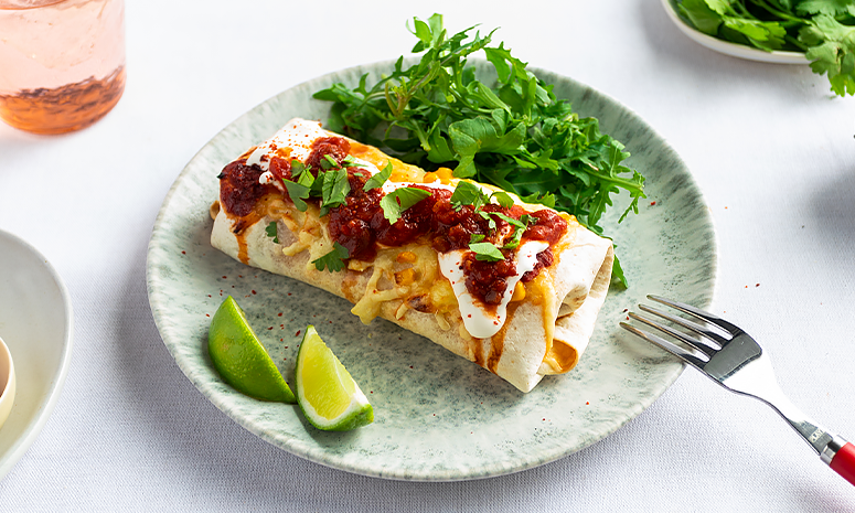 Gratinert tortilla med pulled pork taco, servert på grønnspettet tallerken med limebåter og salat på siden. Tortillaen har rømme, salsa og finhakket koriander på toppen.