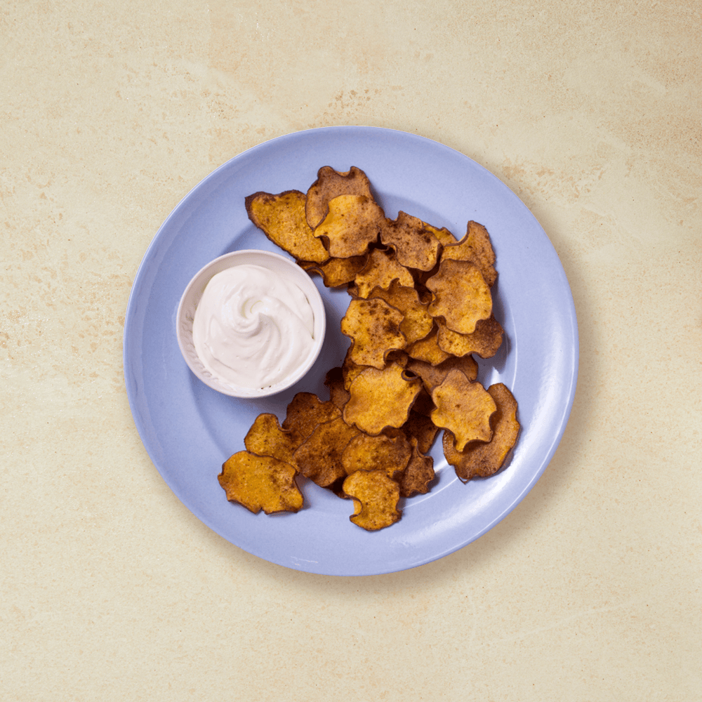 Ovnsbakte søtpotetchips med hint av chili, servert med dip på lys blå tallerken.