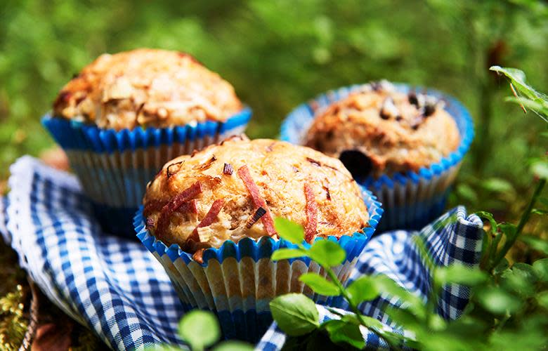 Grove matmuffins med ost, purre og fårepølse i blå og hvite muffinsformer, på blårutete kjøkkenhåndkle i blåbærlyng.