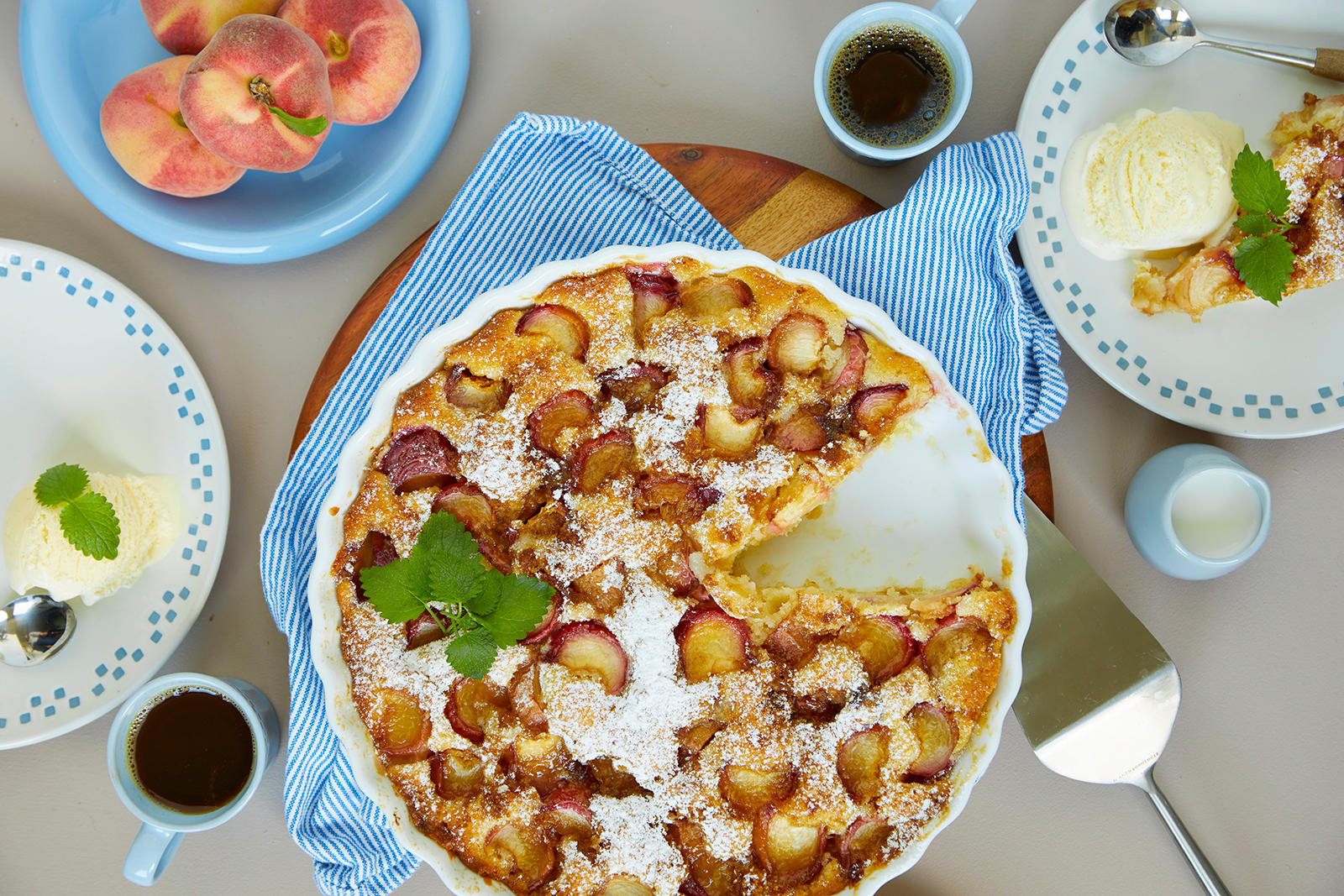 Enkel sommerpai med fersken stekt i rund paiform, og servert på små asjetter med en kule iskrem. Kaffekopper og en liten mugge med fløte ved siden av.