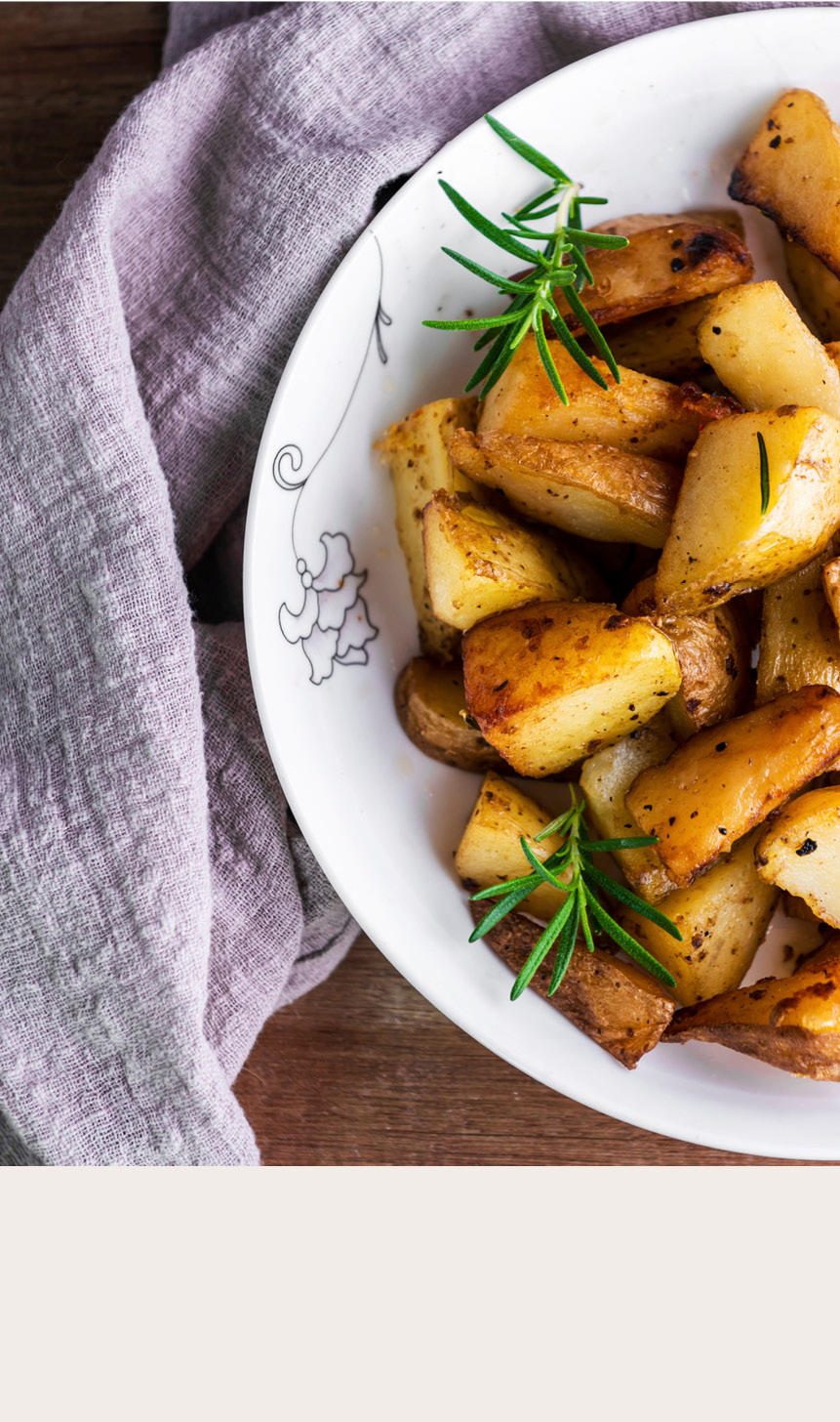 Stekte potetbåter i skål med grønn pynt øverst og beige bakgrunn nederst
