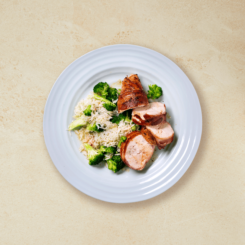 Kyllingfilet med bacon, ris og brokkoli på en hvit tallerken